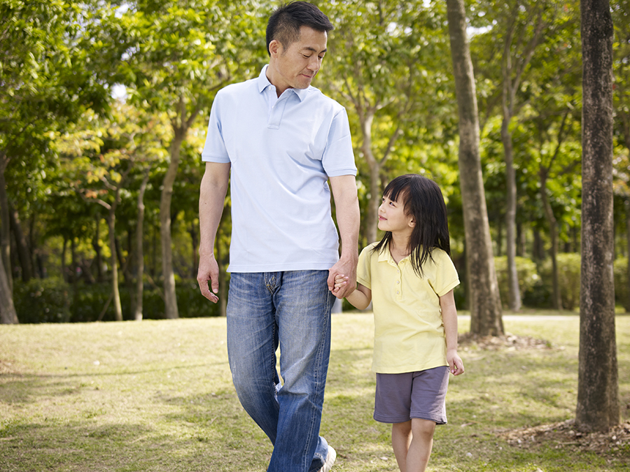 asian father and elementary-age daughter enjoying a walk in nature.